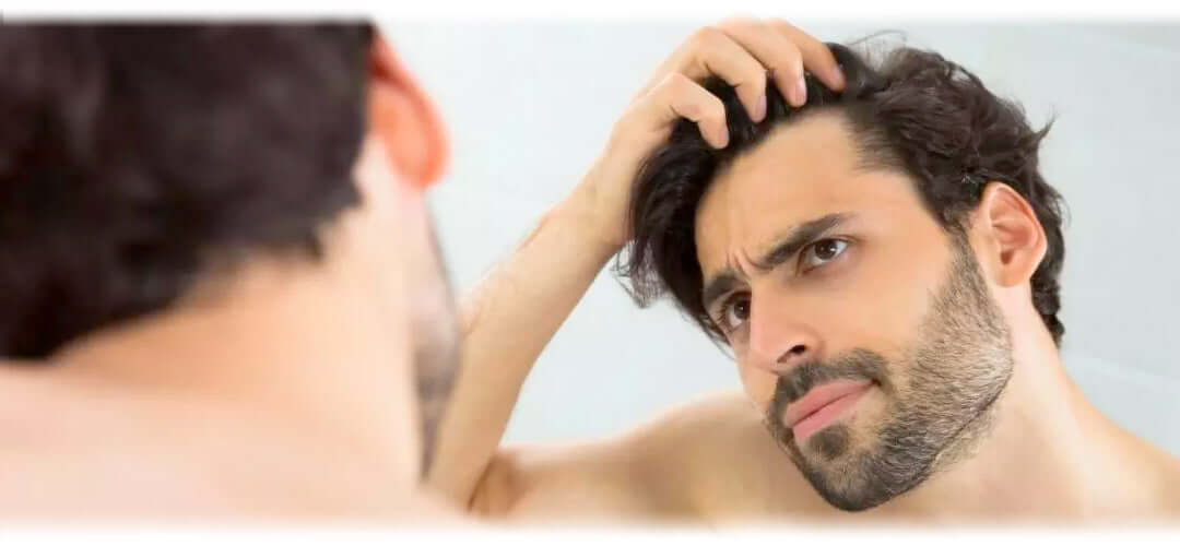 Man examining his hairline in the mirror, seeking solutions to stop hair loss.