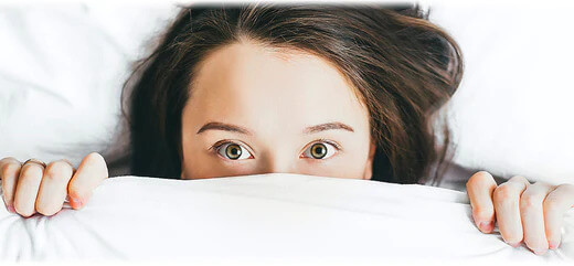 Lady suffering from sleep problems hiding under white duvet cover
