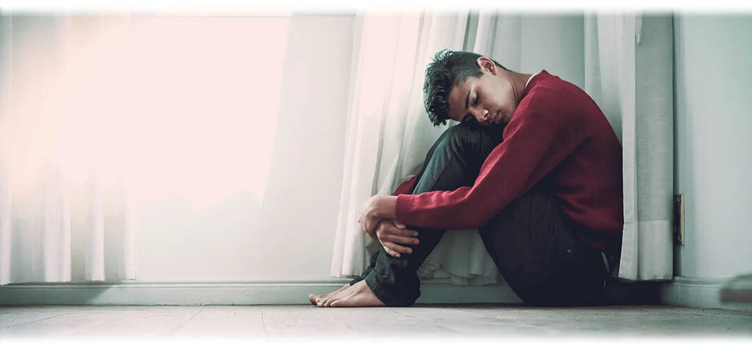 An image representing mental health, featuring a person sitting on the floor forlorn and exhausted