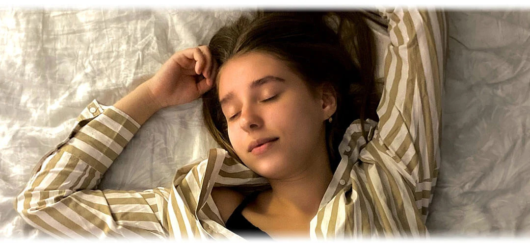 A person lying in bed with eyes closed, surrounded by comfortable pillows and blankets, suggesting a peaceful sleep. The image conveys the importance of sleeping better for overall health and well-being.
