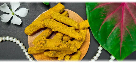 A backdrop of fresh turmeric roots and ground turmeric powder. The image suggests the topic of turmeric and its health benefits