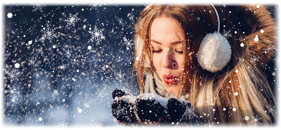 Festive Image of a lady wrapped up with mittens and coat blowing snow off her hands