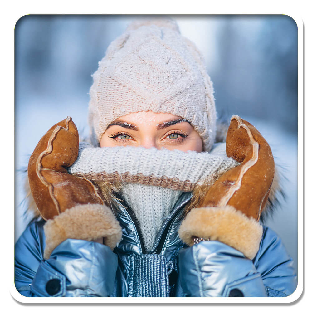 A woman cozily wrapped in winter attire, with a knitted hat and gloves, her breath visible in the cold air, symbolizes robust immunity and the fight against seasonal colds, aligned with Lily & Loaf's commitment to supporting health and wellness during the winter months.