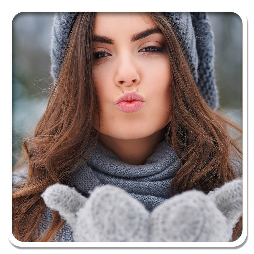 Woman in winter attire blowing a kiss, epitomizing beauty and care in Lily & Loaf's Hair, Skin & Nails products.