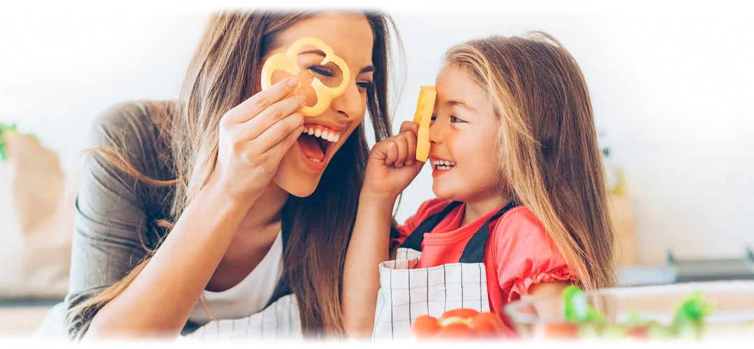 Joyful mother and daughter playing with healthy food, embodying the fun side of Lily & Loaf's wellness journey.
