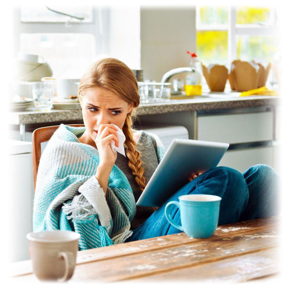 Concerned woman with a cold, holding a tissue and using a tablet, showcasing the need for immune support with Lily & Loaf.