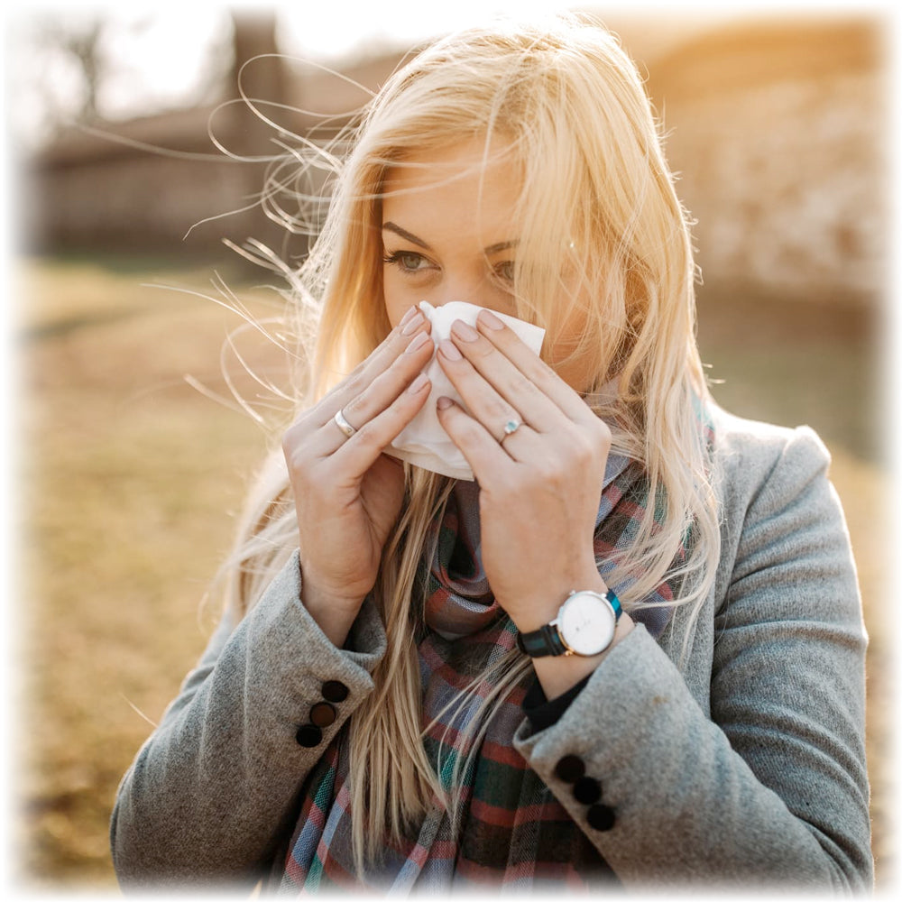 Find relief with Lily & Loaf's natural remedies, woman with allergies using a tissue outdoors.